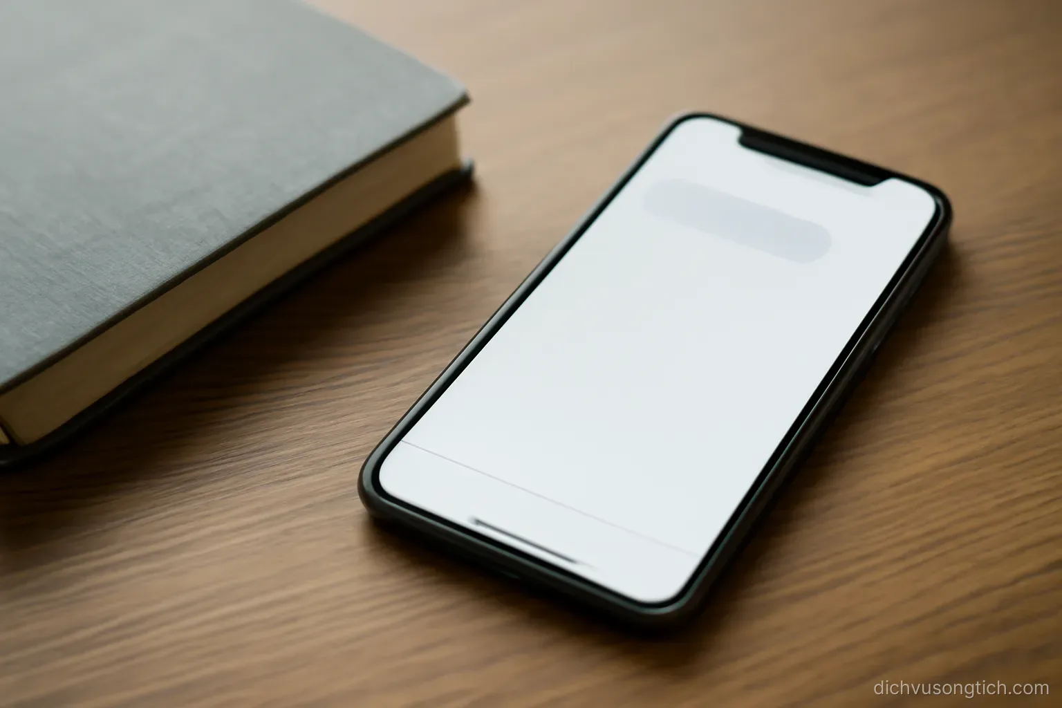 a phone showing an unanswered message thread lying face up on a desk beside a closed notebook