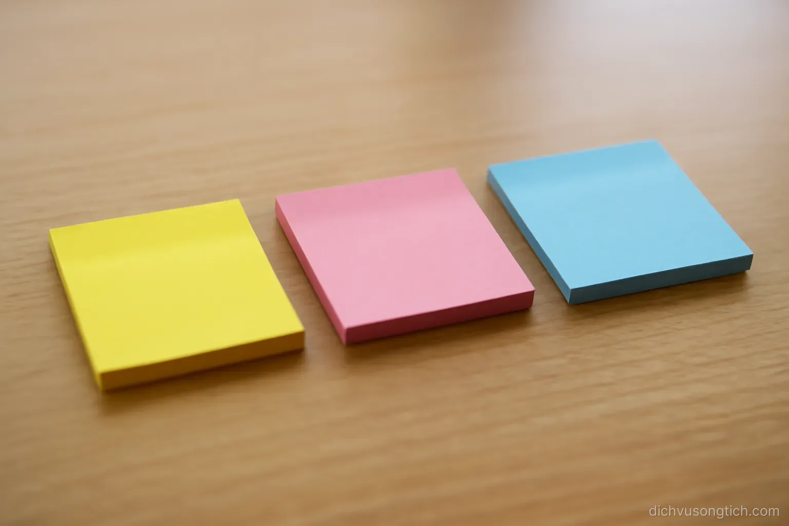 three sticky notes in different colours arranged in a row on a desk surface